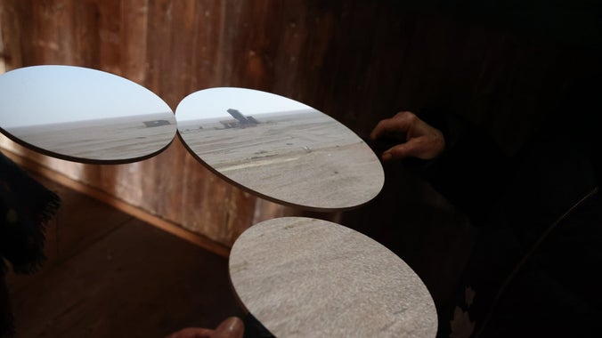 Hands holding different paddles with projections of a Camera Obscura as it is used at Orford Ness